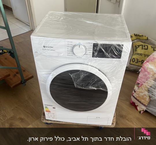 מכונת כביסה עטופה בניילון על רצפת עץ